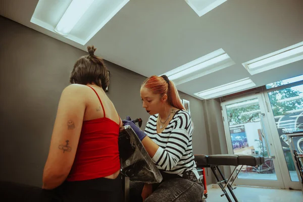 Bella Tatuatrice Con Hari Rosso Tatuare Suo Cliente Studio — Foto Stock