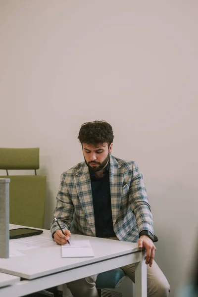 Schöner Geschäftsmann Schreibt Notizen Ins Notizbuch Während Schreibtisch Sitzt — Stockfoto