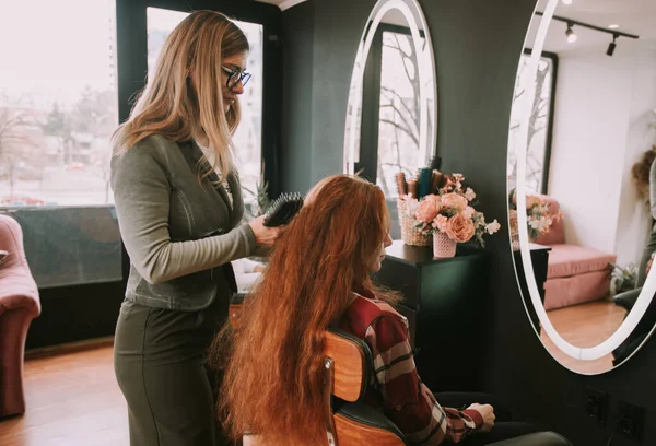一位金发美发师正准备在沙龙里给她的客户刷红头发 — 图库照片
