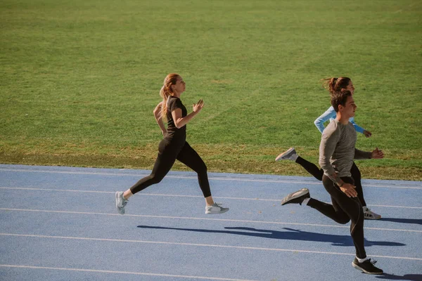 Three Friends Running Blue Sports Track — стоковое фото