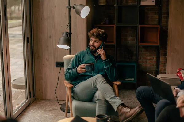 Gülümseyen Yakışıklı Erkek Bir Telefon Görüşmesi Yapıyor Otururken Bir Fincan — Stok fotoğraf
