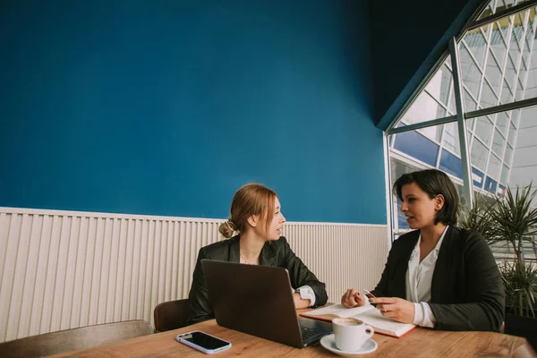 Dos Mujeres Negocios Hablando Oficina Mientras Están Sentadas Con Portátil — Foto de Stock