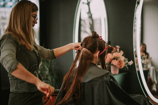 金发美发师在美发厅用梳子刷客户的头发 — 图库照片
