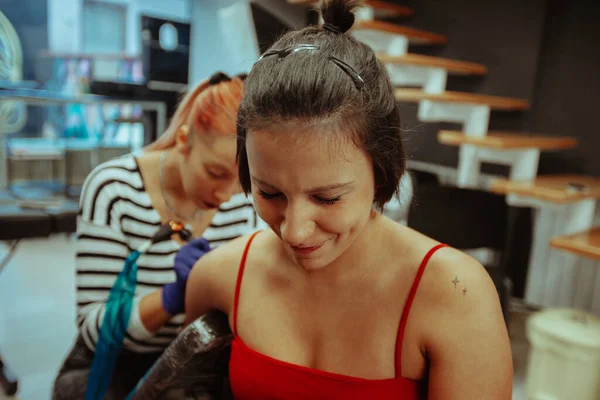 Close Linda Garota Morena Fazendo Rostos Enquanto Faz Uma Tatuagem — Fotografia de Stock