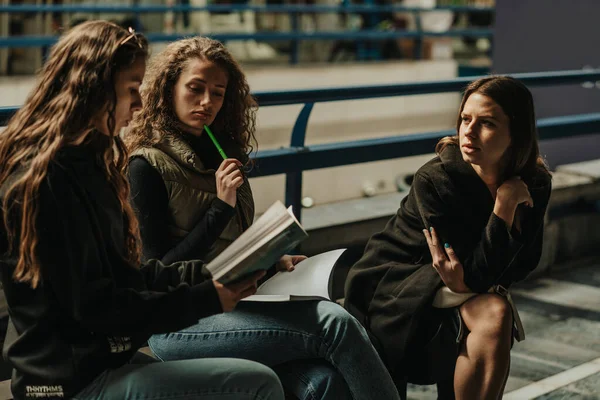美しいですブルネットの女の子読書A本の話へ彼女の友人に座っている間にベンチ — ストック写真