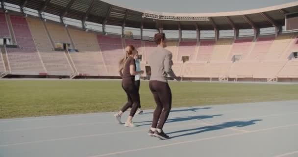 Троє Людей Розтягуються Крутяться Ногами Щоб Підготуватися Бігу Стадіоні — стокове відео