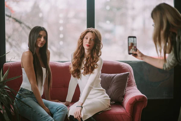 ブロンド美容師撮影彼女の携帯電話とともに彼女の二つのモデルとともに赤と茶色の長い髪 — ストック写真