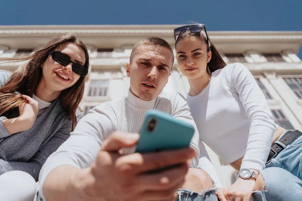 Fechar Três Amigos Olhando Para Telefone Enquanto Sentado Fora — Fotografia de Stock
