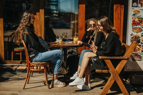三个可爱的女孩在咖啡吧边聊天边微笑的侧视图 — 图库照片