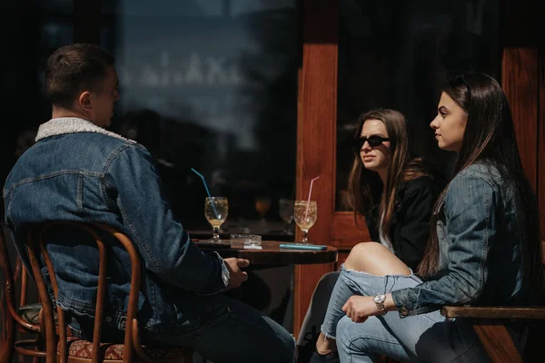 市内中心部のカフェに座っている3人の友人1人の男の子と2人の女の子 — ストック写真