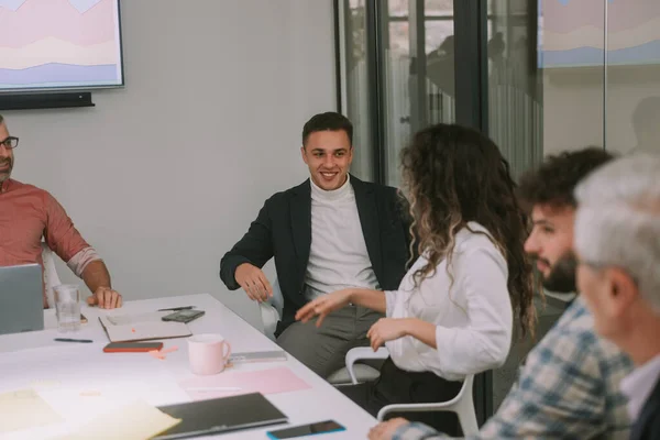 사업가가 웃으면서 동료와 이야기를 나누고 사무실의 비즈니스 테이블에 — 스톡 사진