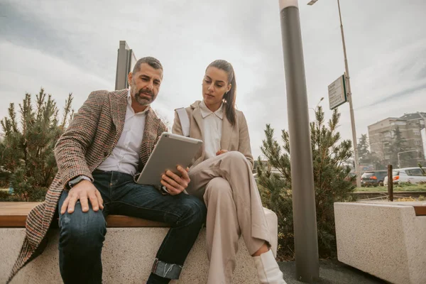 Dois Colegas Negócios Olhando Para Tablet Enquanto Estavam Sentados Fora — Fotografia de Stock