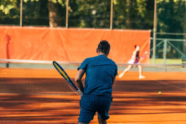 青いスポーツウェアを身に着けている粘土裁判所で提供する準備ができてテニス選手のレビュー — ストック写真
