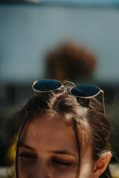 彼女の頭の上にサングラスでブルネットの女の子のショットを閉じます ぼやけた背景 — ストック写真