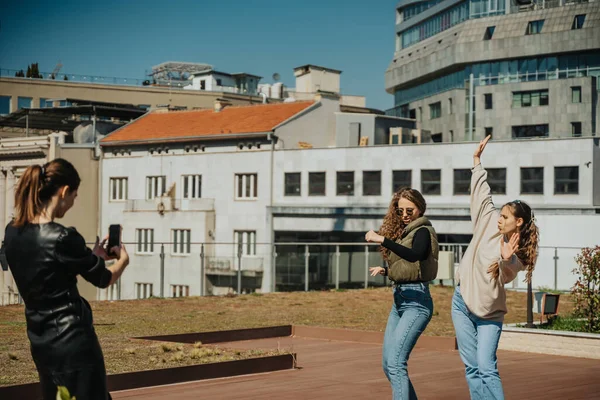 友達が写真を撮っている間に二人の女の子が外で踊っている — ストック写真