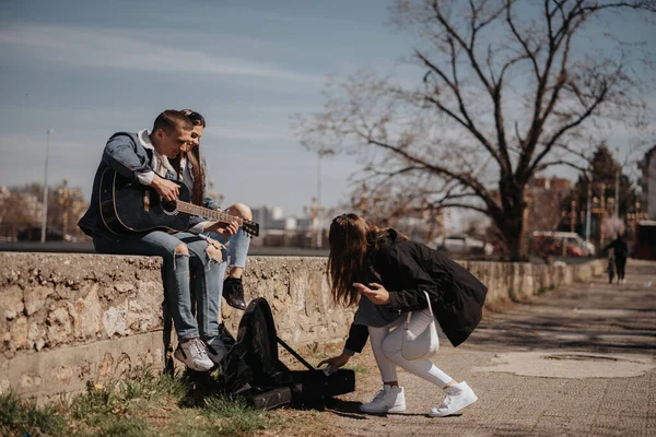 Brünettes Mädchen Gibt Dem Schönen Musikpaar Das Park Sitzt Geld — Stockfoto