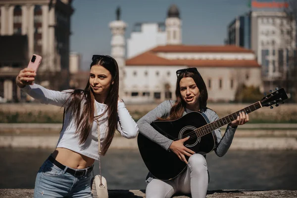女孩和她的朋友在河边弹奏吉他手时的亲密接触 — 图库照片