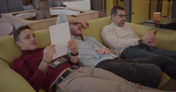 Diversos Compañeros Edad Descansando Mientras Están Acostados Cómodo Sofá Oficina — Vídeos de Stock