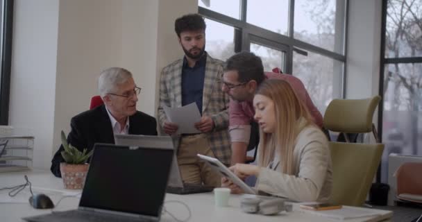 現代的なオフィススペースで若い従業員と一緒に働くシニアビジネスマン — ストック動画
