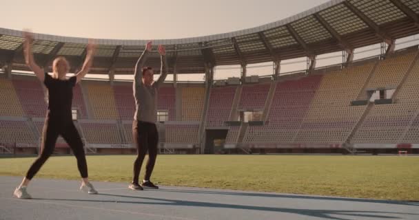 Stadyumda Koşmadan Önce Iki Genç Atlama Hareketleri Yapıyor Kaslarını Esnetiyor — Stok video
