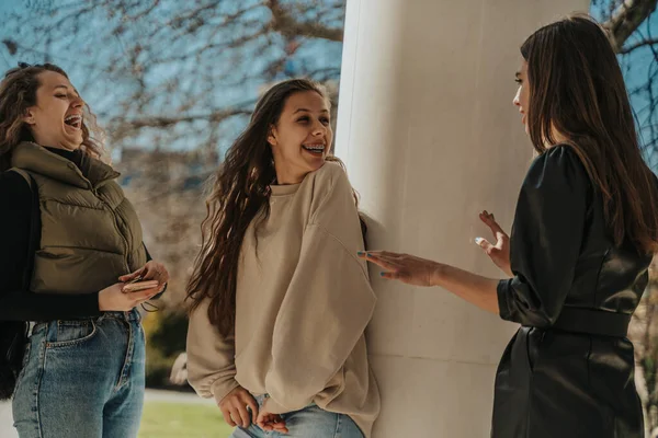 Lovely Girls Laughing While Listening Friend Black Overcoat Explaining Fun — Stock Photo, Image