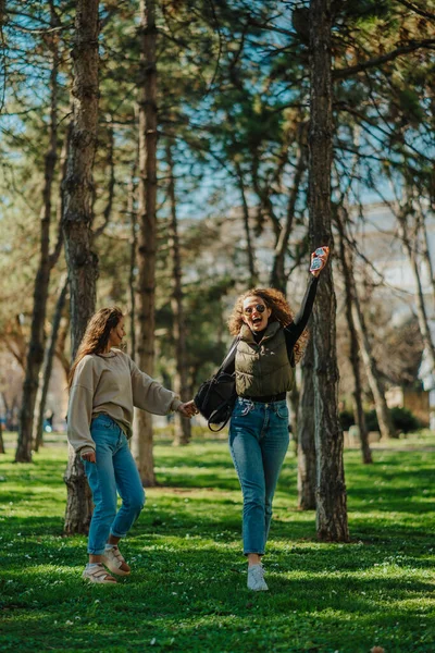 两个女孩在公园里玩的前景照片 布鲁内特姑娘回头看过去 而她那金发卷发的朋友却在幸福地尖叫着 — 图库照片