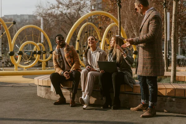 Skupina Čtyř Kolegů Mluví Nějaké Obchodní Plány Zatímco Sedí Parku — Stock fotografie