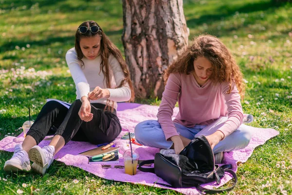 公园里漂亮的女学生坐在紫色毯子上 — 图库照片