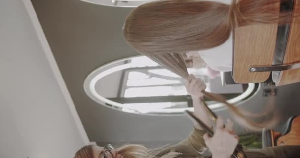 Μαλλιά Σιδερώματος Ενός Μελαχρινού Κοριτσιού Ένα Σαλόνι Κάθετη Βίντεο — Αρχείο Βίντεο