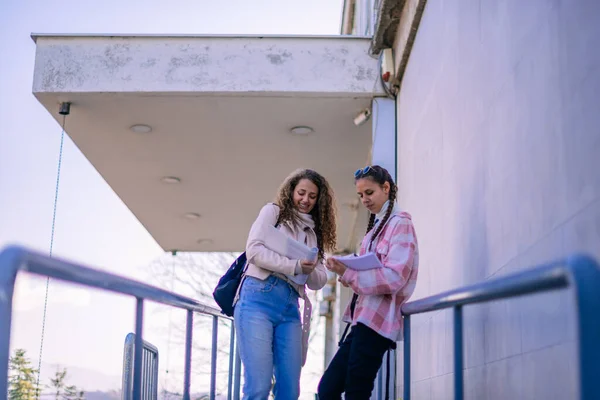 建物の階段に立って本を持っている2人の若い女子高生 — ストック写真