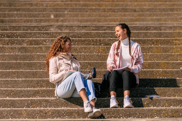 階段に座って会話をしている女子高生二人 — ストック写真