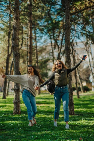 Φωτογραφία Δύο Όμορφων Χαμογελαστών Κοριτσιών Που Αράζουν Στο Πάρκο Απλωμένα — Φωτογραφία Αρχείου