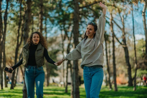 Δύο Κορίτσια Αράζουν Στο Πάρκο Χαμογελάνε Και Κρατάνε Χέρια Τους — Φωτογραφία Αρχείου
