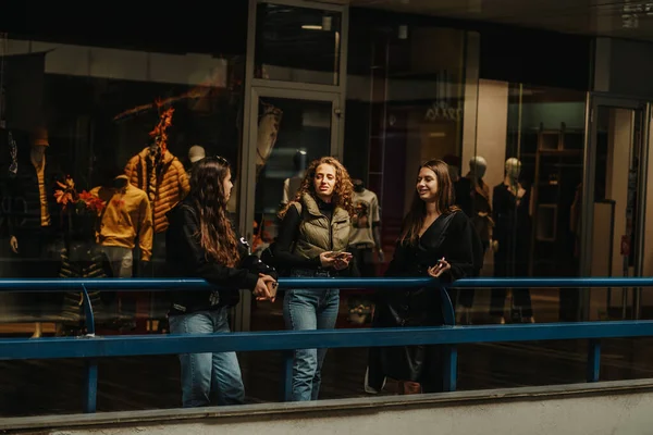 Três Meninas Discutindo Moda Enquanto Apoiam Uma Cerca Azul Shopping — Fotografia de Stock