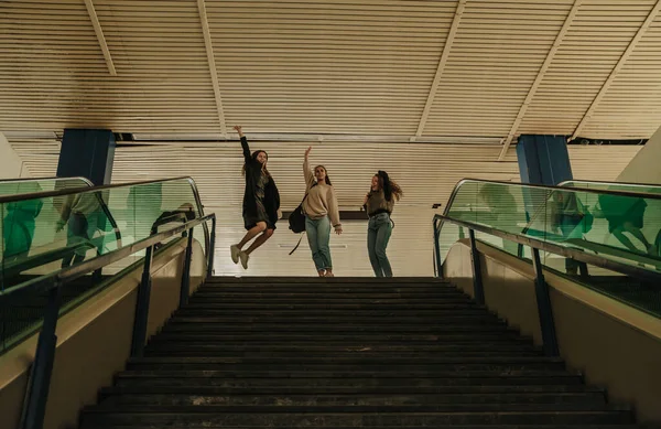 三个快乐的女孩在下楼到购物中心之前跳了起来 — 图库照片