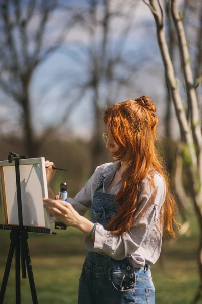 公園のイーゼルに描かれたジンジャー女性画家 — ストック写真