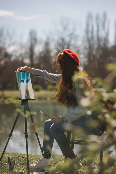 Ginger Dívka Malování Stojan Zatímco Sedí Židli Parku Jezera — Stock fotografie