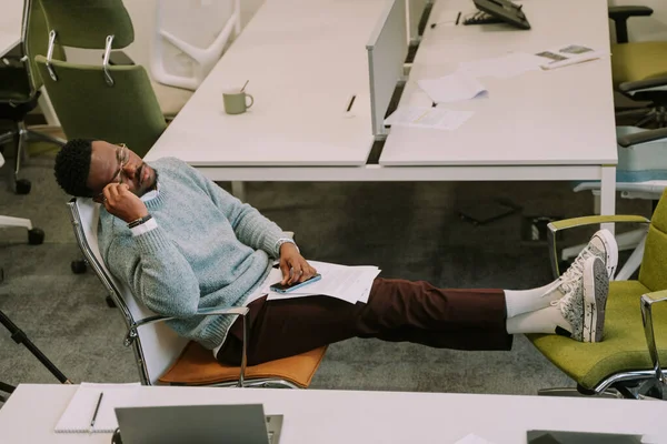 オフィスで寝てる 若い黒人男性は仕事で毎日の仕事の後に疲れているので 彼は昼寝をした — ストック写真