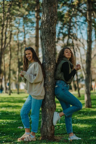 Δύο Κορίτσια Ακουμπάνε Ένα Δέντρο Στο Πάρκο Και Κρατούν Ένα — Φωτογραφία Αρχείου