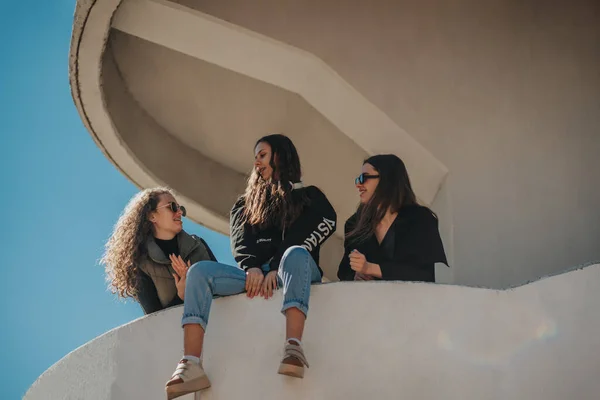 Τρία Κορίτσια Συζητούν Πανέμορφο Κορίτσι Που Κάθεται Έναν Τοίχο Κτιρίου — Φωτογραφία Αρχείου