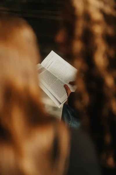友人と街のベンチに座っている間に本を読んでいる豪華な長い髪のブルネットの女の子 撃たれた — ストック写真