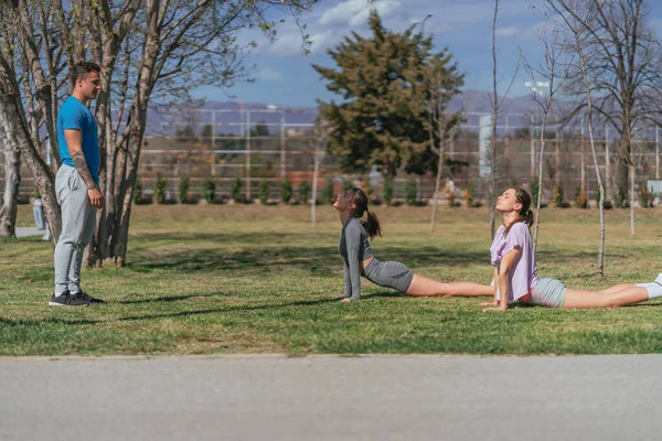 公園で体を行使するスポーツ少女 男性フィットネスインストラクターが見ている — ストック写真