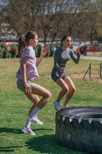 Вид Сбоку Двух Здоровых Сексуальных Девушек Прыгающих Шине Грузовика Упражнение — стоковое фото
