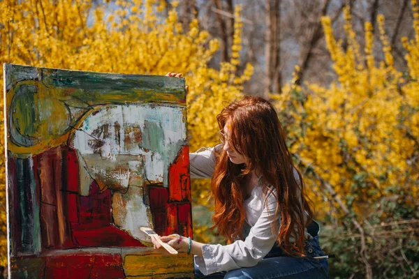 在公园里 一个漂亮的姜姑娘正在画一幅色彩斑斓的大图画 — 图库照片