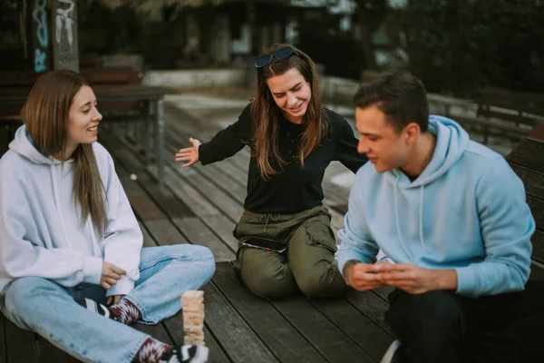Drei Freunde Lächeln Beim Jenga Spielen Auf Der Holzbank — Stockfoto