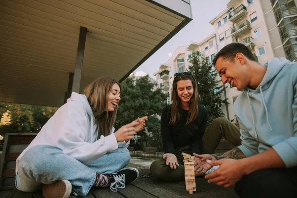 Drei Beste Freunde Lächeln Beim Jenga Spielen Auf Der Holzbank — Stockfoto