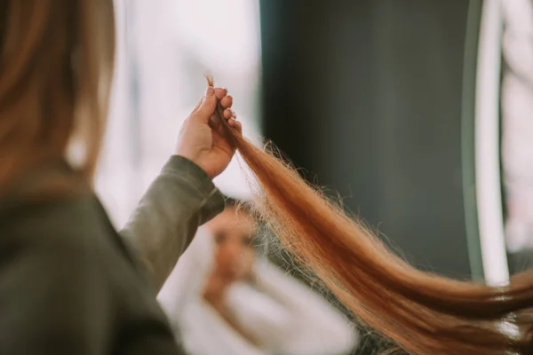 靠近金发美发师站在美发厅边看受损的红头发 — 图库照片