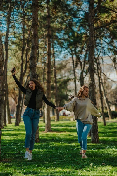 Φωτογραφία Δύο Κοπέλες Αράζουν Στο Πάρκο Τραγουδούν Και Πηδάνε Ενώ — Φωτογραφία Αρχείου