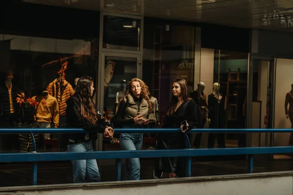 Três Garotas Apoiando Uma Cerca Azul Shopping Center Discutindo Moda — Fotografia de Stock