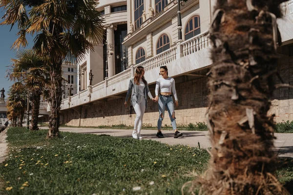 Duas Garotas Bonitas Andando Parque Enquanto Seguram Mão Conversam — Fotografia de Stock